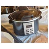 Slow cooker with digital display, baking dish, cutting boards, and floral arrangement