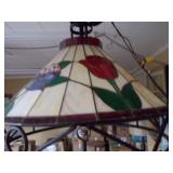 This is a Tiffany-style stained glass hanging pendant light fixture with a floral motif and a wrought iron frame
