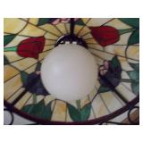 This is a Tiffany-style stained glass hanging pendant light fixture with a floral motif and a wrought iron frame