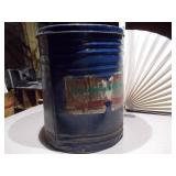 The can is a large, blue metal drum with a heavily worn paper label