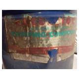 The can is a large, blue metal drum with a heavily worn paper label