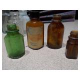 The image displays a collection of vintage glass bottles and shot glasses