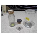 The image displays a collection of vintage glass bottles and shot glasses