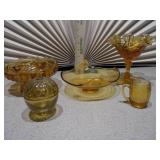 The image displays a collection of vintage amber glass items, including a ruffled compote, a basket dish, a covered candy dish, and a small mug