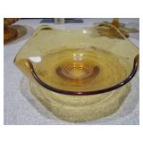 The image displays a collection of vintage amber glass items, including a ruffled compote, a basket dish, a covered candy dish, and a small mug