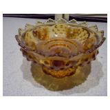 The image displays a collection of vintage amber glass items, including a ruffled compote, a basket dish, a covered candy dish, and a small mug