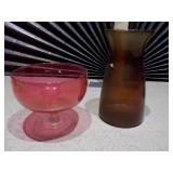 This collection features various pieces of cranberry glass stemware and vases