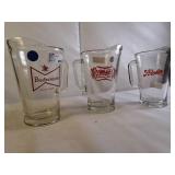 Three vintage-style beer pitchers from different breweries incliding Budweiser King of Beers glass pitcher