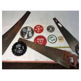 A collection of cutting tools, primarily circular saw blades for power saws and traditional hand saws.