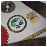 A collection of cutting tools, primarily circular saw blades for power saws and traditional hand saws.