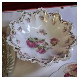 Collection of vintage porcelain and glass dishes, featuring various floral patterns, gilded rims, and crystal designs.