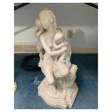 Woman seated tending to a child, 14...