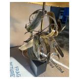 This Lot is a 1970s Hollywood Regency-style table lamp, featuring a sculpted metal base and a pleated shade