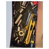 Red metal toolbox with assorted hand tools and accessories including pliers, screwdrivers, a utility knife, and a socket set