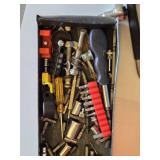 Red metal toolbox with assorted hand tools and accessories including pliers, screwdrivers, a utility knife, and a socket set