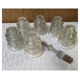 Six vintage clear glass insulators, specifically resembling the Hemingray-45 model based on their shape and color and a pin glass insulator.
