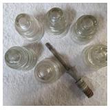 Six vintage clear glass insulators, specifically resembling the Hemingray-45 model based on their shape and color and a pin glass insulator.