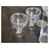 Various Glasses, Some Plastic and Goblets Including Skeleton Hand Stand and Bullet Embedded Tumblers