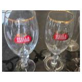 Mixed glassware including Stella Artois glasses, wine glasses with green stems, and a decorative bottle with a crown top.
