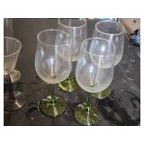 Mixed glassware including Stella Artois glasses, wine glasses with green stems, and a decorative bottle with a crown top.