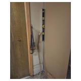a level tool, pipe wrench, and a long wooden stick leaning