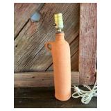 terracotta ceramic bottle lamp featuring a curved handle.