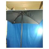 Brand New  Market Patio Umbrella. It features a dark colored canopy supported by a multi-rib metal frame structure