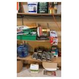 Contents of wooden shelves, including:- various paints- gloss trim- Wheaties box- board games- decorative outdoor lighting- tools- vacuum- mini shop back