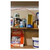 Contents of wooden shelves, including:- various paints- gloss trim- Wheaties box- board games- decorative outdoor lighting- tools- vacuum- mini shop back