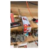 Contents of wooden shelves, including:- various paints- gloss trim- Wheaties box- board games- decorative outdoor lighting- tools- vacuum- mini shop back