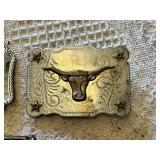Western-themed belt buckles including intricate wagon design, longhorn motif, and a rhinestone-studded buckle