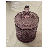 Artificial lavender plant in a black pot, set of purple glasses, and a purple glass container with lid