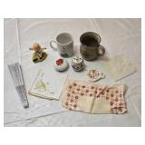 Decorative Collectibles and Mugs Including Minnesota Public Radio Mug, Ceramic Figurine, Embroidered Cloths and a Hand Fan