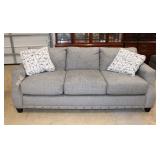  Lot 156 New Broyhill 3 cushion upholstered sofa with industrial tacking and decorative pillows in t