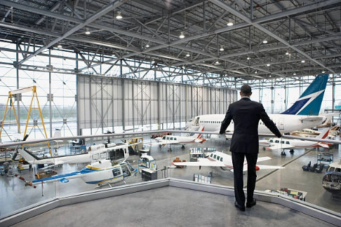 man standing in a hangar looking at planes