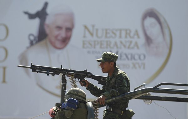 soldiers keep watch near a large poster promoting the visit of pope benedict xvi in leon