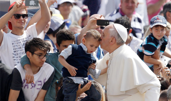 Pope Francis kisses a boy as he arrives for his weekly general audience in St. Peter's Square at the Vatican June 5. (CNS photo/Paul Haring) (June 5