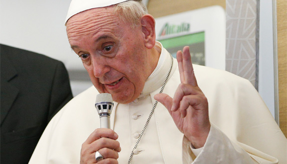 Pope Francis gestures as he answers questions from journalists aboard his flight from Bangui