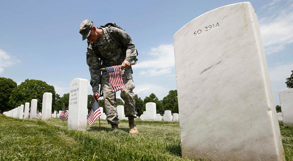 Third U.S. Infantry Regiment member places flags on graves during 'Flags-In' ceremony at Arlington National Cemetery