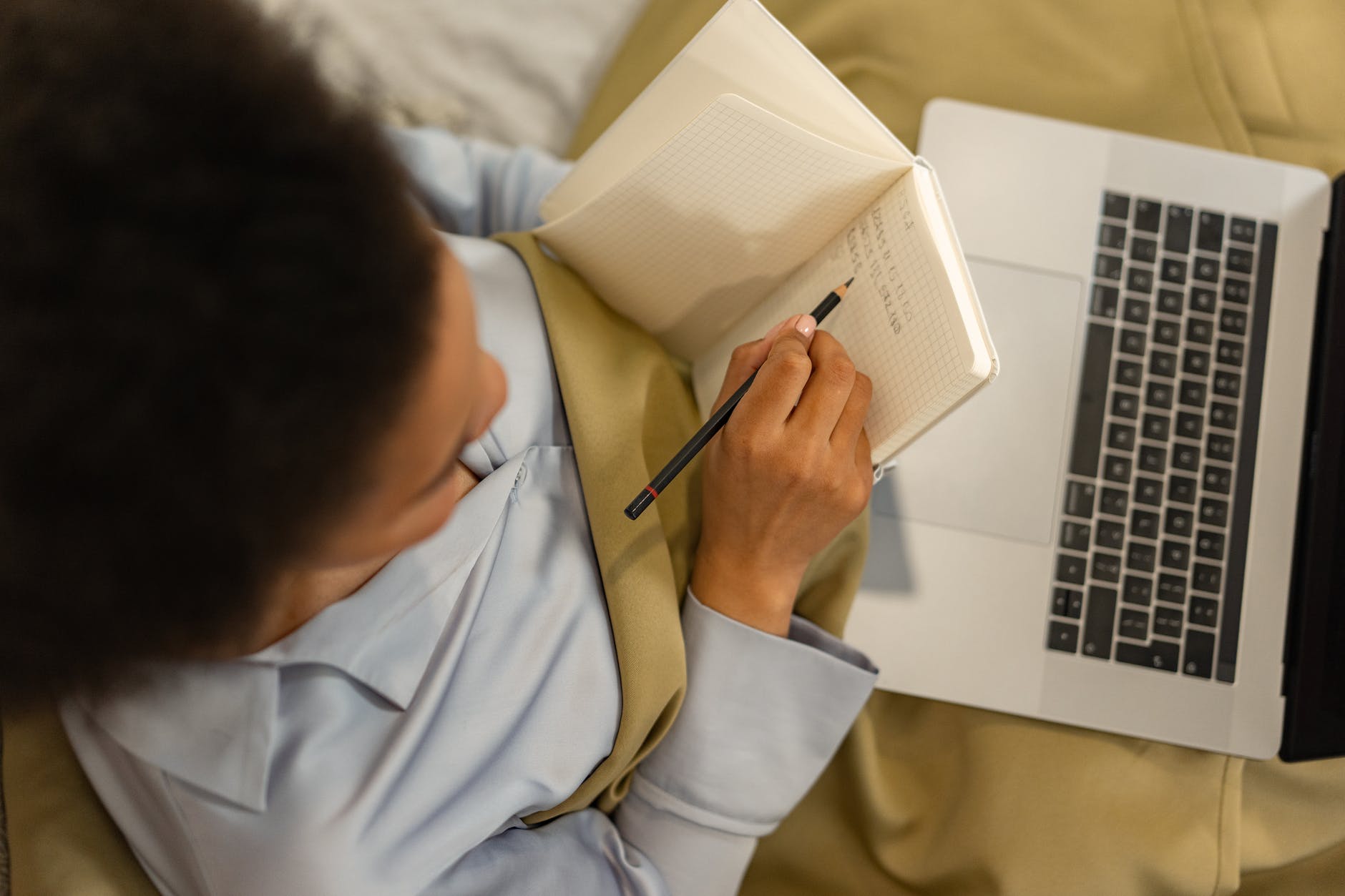 a person writing on notebook using a pencil