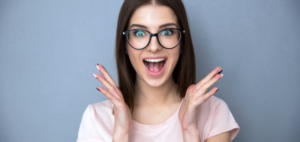 Surprised,Young,Woman,In,Glasses,Over,Gray,Background