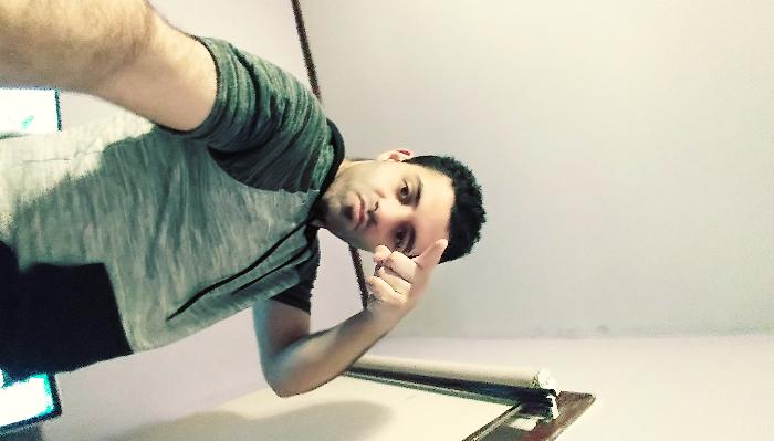 A young man taking a low-angle selfie while pointing toward the camera.