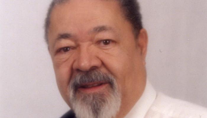 Close-up portrait of an older Black man with a grey goatee and a gentle smile.