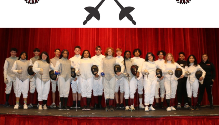A diverse youth fencing team in white gear holding masks stands on a stage in front of a red curtain.