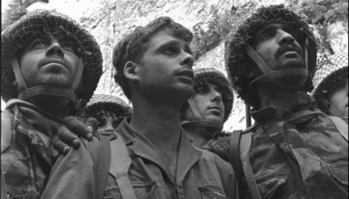 Three Israeli paratroopers in uniform look up with emotion while standing at the Western Wall.