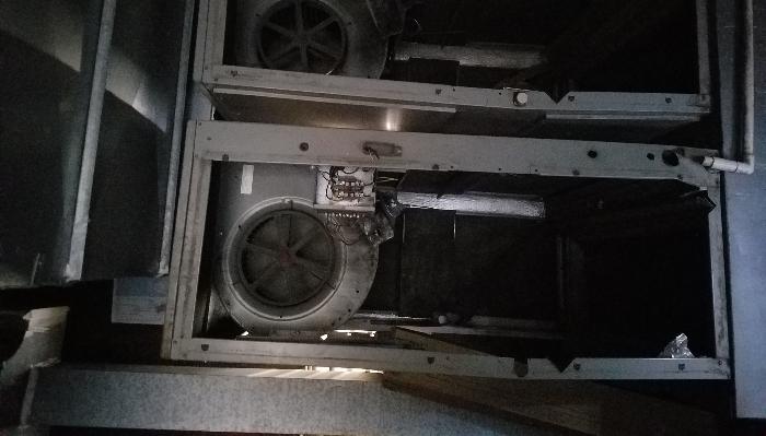 Old, dark commercial HVAC air handler unit with exposed blower fans and internal wiring.