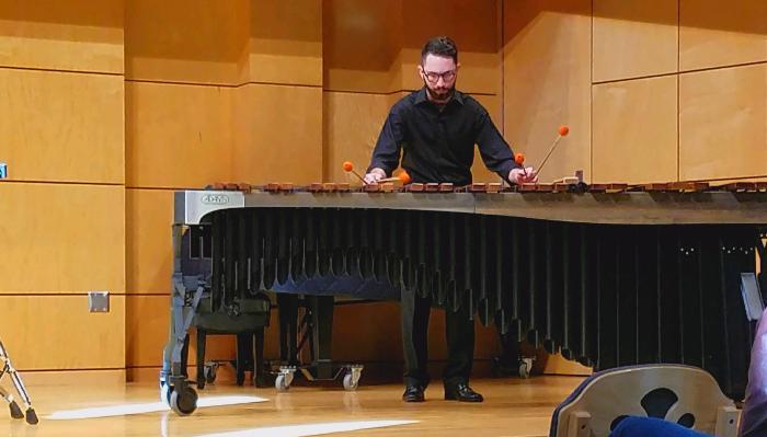 A musician playing a large marimba on a concert stage using four mallets.