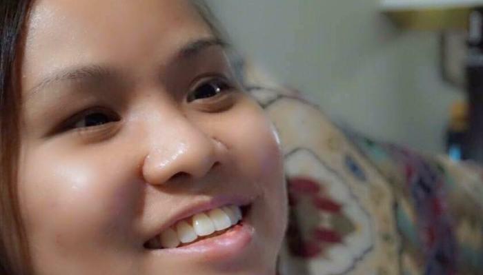 Close-up of a young woman smiling warmly as she looks upward.