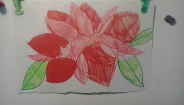 Child's marker drawing of a large pink and red flower with green leaves on white paper.