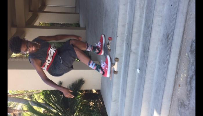 A young skateboarder mid-air performing a trick over a set of concrete outdoor stairs.